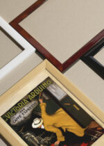 Widok z góry na cztery drewniane ramki, w jednej z nich oprawiony plakat La Victoria Arduino per Caffè Espresso Leonetto Cappiello 1922