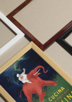 Widok z góry na cztery drewniane ramki, w jednej z nich oprawiony plakat Végétaline kucharz na słoniu Leonetto Cappiello