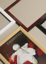 Widok z góry na cztery drewniane ramki, w jednej z nich oprawiony plakat Leonetto Cappiello Cigarettes orientalny mędrzec 1901