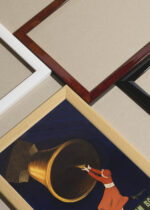 Widok z góry na cztery drewniane ramki, w jednej z nich oprawiony plakat Liqueur Dom Bosco Leonetto Cappiello 1906