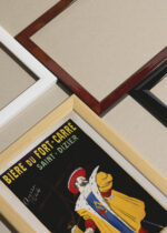 Widok z góry na cztery drewniane ramki, w jednej z nich oprawiony plakat Bière du Fort Carré Leonetto Cappiello 1911