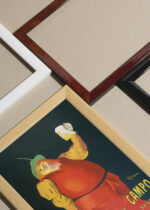 Widok z góry na cztery drewniane ramki, w jednej z nich oprawiony plakat La Cruz del Campo Leonetto Cappiello piwo