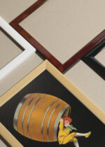 Widok z góry na cztery drewniane ramki, w jednej z nich oprawiony plakat Leonetto Cappiello kobieta z beczką reklama vintage