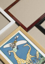 Widok z góry na cztery drewniane ramki, w jednej z nich oprawiony plakat Moriz Jung polowanie na żyrafy samolotem surrealizm secesja