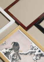 Widok z góry na cztery drewniane ramki, w jednej z nich oprawiony plakat jastrząb na ośnieżonej gałęzi Ohara Koson japoński vintage