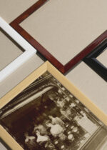 Widok z góry na cztery drewniane ramki, w jednej z nich oprawiony plakat E. Atget witryna salonu fryzjerskiego Paryż 1912