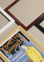 Widok z góry na cztery drewniane ramki, w jednej z nich oprawiony plakat Vignettes of Manhattan (1895)