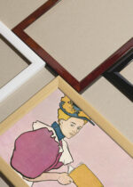 Widok z góry na cztery drewniane ramki, w jednej z nich oprawiony plakat Kobieta trzymająca książkę (1896)