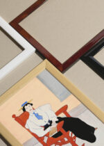 Widok z góry na cztery drewniane ramki, w jednej z nich oprawiony plakat Kobieta na czerwonym fotelu bujanym (ok. 1895)