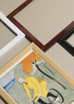 Widok z góry na cztery drewniane ramki, w jednej z nich oprawiony plakat Mężczyzna na rowerze (1894)