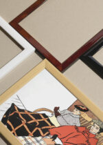 Widok z góry na cztery drewniane ramki, w jednej z nich oprawiony plakat Kobieta i mężczyzna siedzący pod kocami (1897)