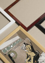 Widok z góry na cztery drewniane ramki, w jednej z nich oprawiony plakat Mężczyzna czytający książkę (ok. 1890-1907)