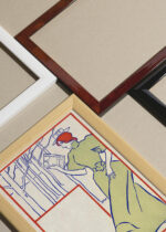 Widok z góry na cztery drewniane ramki, w jednej z nich oprawiony plakat Kobieta w zielonej sukni czytająca książkę (1895)