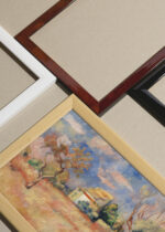 Widok z góry na cztery drewniane ramki, w jednej z nich oprawiony plakat Renoir Gołębnik w Bellevue 1888 pejzaż francuski