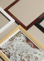 Widok z góry na cztery drewniane ramki, w jednej z nich oprawiony plakat mapa-gra planszowa arktyczna Noordpool 40 z 1652 roku