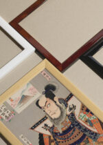 Widok z góry na cztery drewniane ramki, w jednej z nich oprawiony plakat samuraj Toyohara Kunichika ukiyo-e kabuki